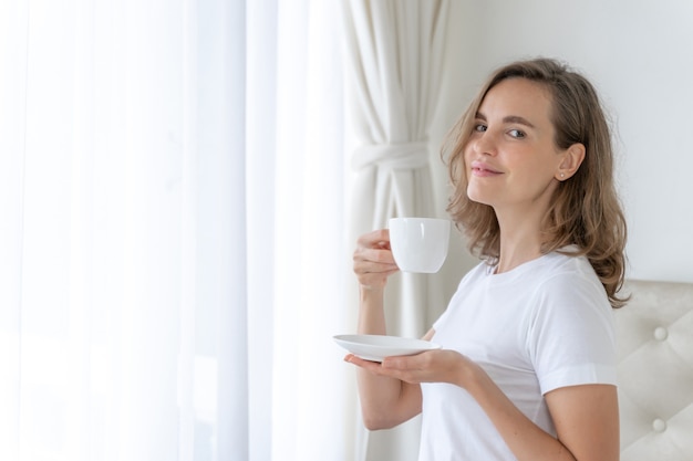 美しい美女かわいい女の子は朝のコーヒーを飲んで幸せを感じます