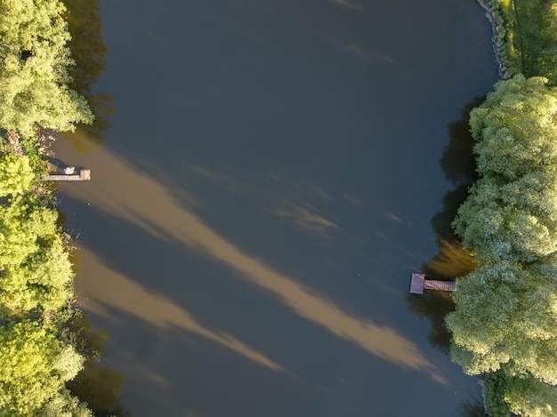 Красивый вид с высоты птичьего полета на Зеленый лес с деревянными рыбацкими мостиками с выходом к реке в солнечный день. Снято дронами.