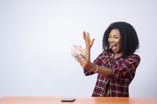 Beautiful black woman holding and looking at the money in her hand