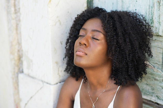 Beautiful Black Woman Relaxing at Wooden Wall