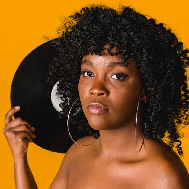 Beautiful black young woman with music plate on colored background