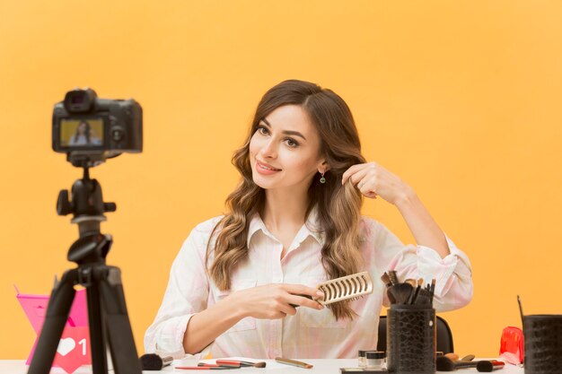 Beautiful blogger brushing hair on camera