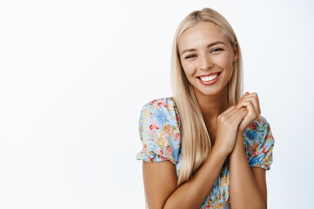 Beautiful blond girl looking with affection smiling coquettish posing in dress against white background Copy space