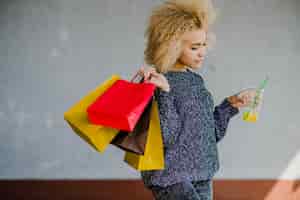 Free photo beautiful blond woman holding drink and paper bags