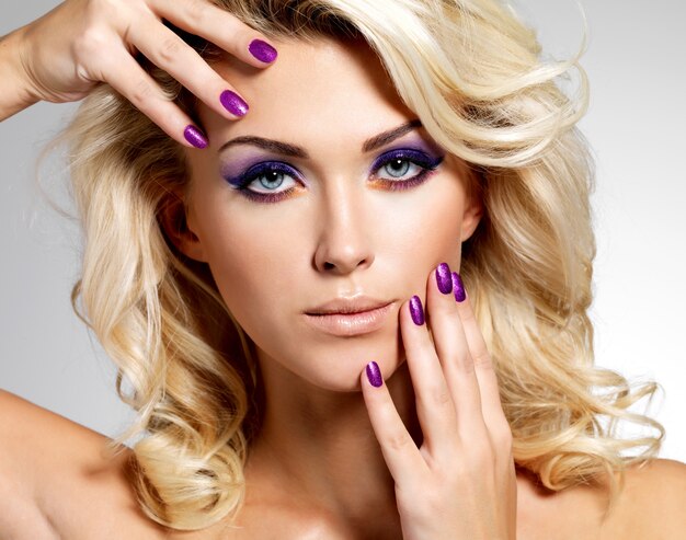 Красивая блондинка женщина с красотой фиолетовый маникюр и макияж глаз