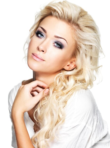 Beautiful blond woman with long curly hair and style makeup. Girl posing on white space