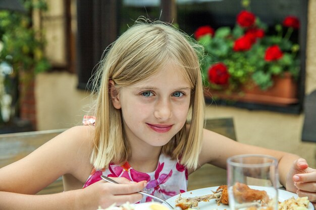 Beautiful blonde child sitting next to a dining table