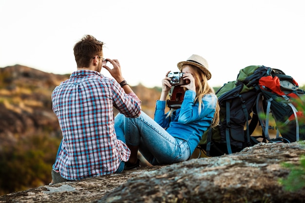 Beautiful blonde female photographer taking picture of boyfriend, canyon background