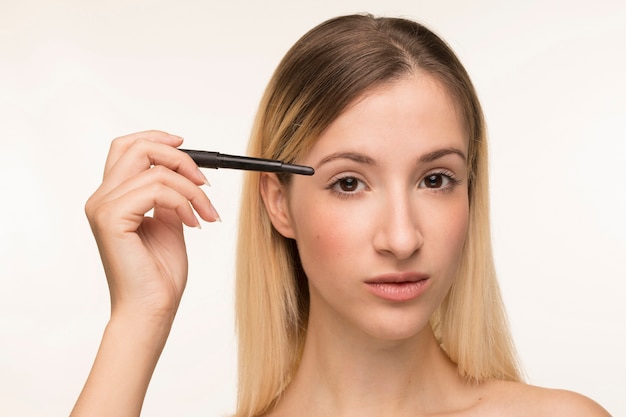 Beautiful blonde girl holding eyeliner