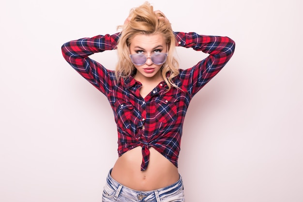 Beautiful blonde girl in red t-shirt and short jeans in brilliant sunglasses isolated on pink