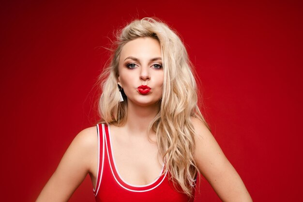 Beautiful blonde in a red swimsuit with bright makeup and red lips