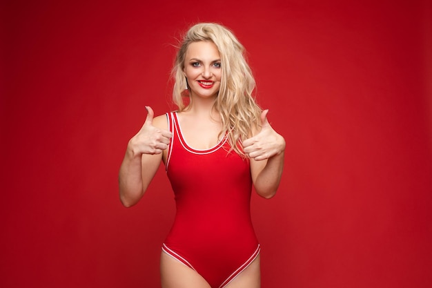 Beautiful blonde in a red swimsuit with bright makeup and red lips