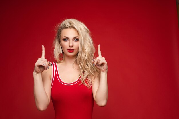 Beautiful blonde in a red swimsuit with bright makeup and red lips