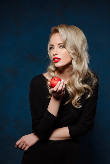 Beautiful blonde woman in black dress holding apple