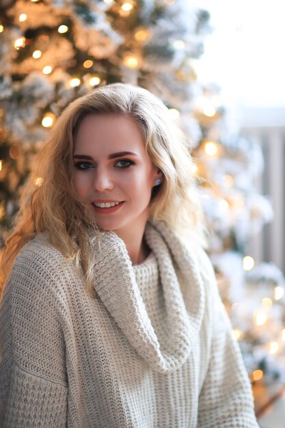Beautiful blonde woman next to the Christmas tree.