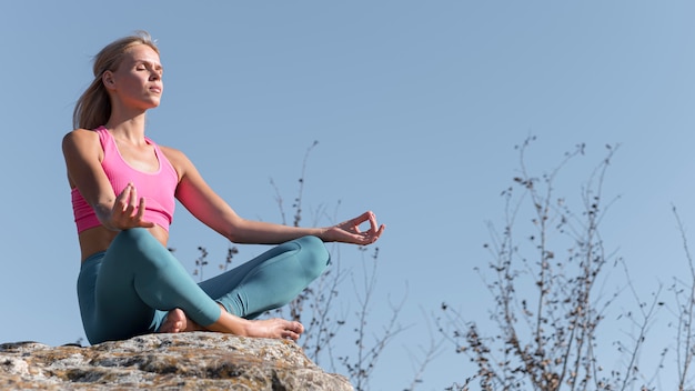 Beautiful blonde woman doing yoga outdoors