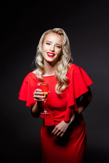 Beautiful blonde woman in evening dress smiling, holding champaign glass