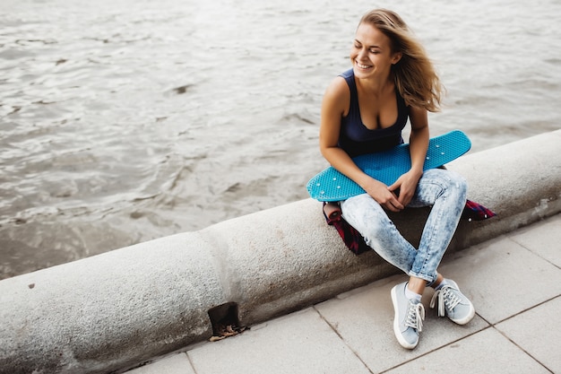 beautiful blonde woman posing with a skateboard