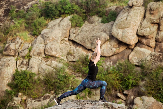 峡谷の岩の上のヨガのアーサナを練習して美しいブロンドの女性