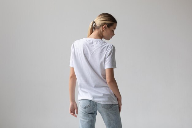 Beautiful blonde woman in a white tshirt and blue jeans posing on a white background