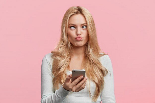 Beautiful blonde woman with white shirt holding phone