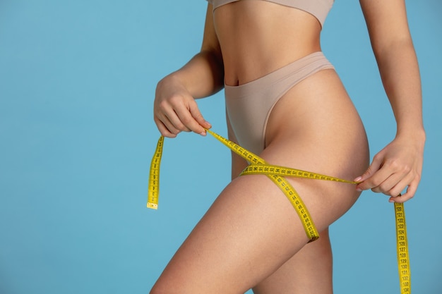 Beautiful body of young caucasian woman isolated on blue  background.