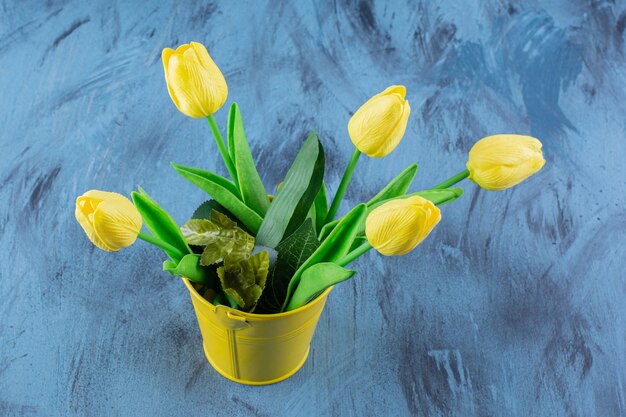 Beautiful bouquet of fresh yellow tulips on blue .