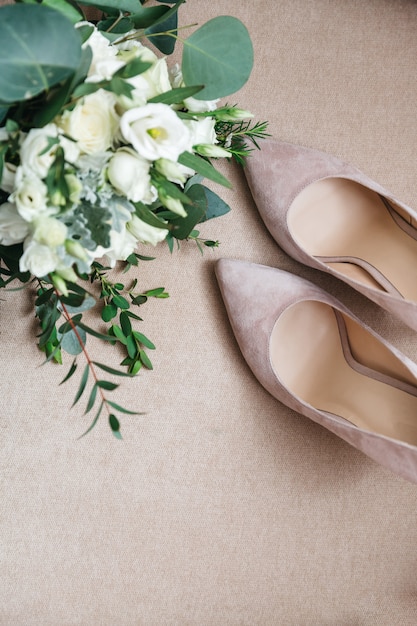 Belle scarpe da sposa sono in piedi accanto a un mazzo di fiori