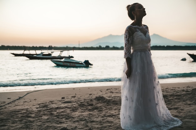 beautiful bride on the beach behind sea at sunset