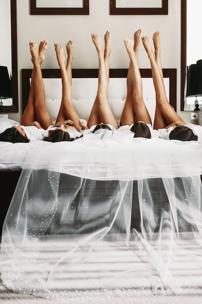 Free photo beautiful bride & bridesmaids showing off sexy legs on bed