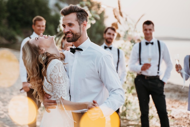 Bellissimi sposi che festeggiano il loro matrimonio con gli ospiti su una spiaggia