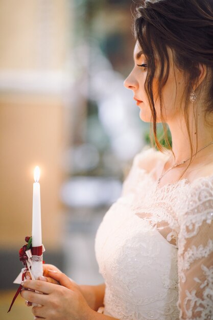 Beautiful bride holds shining candle in her arms during the ceremony
