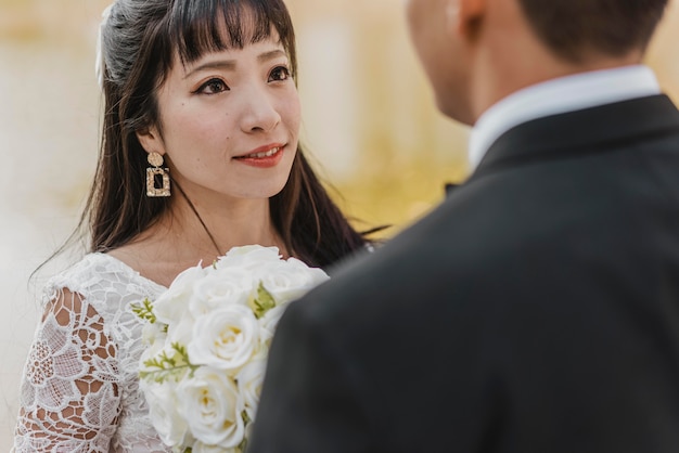 花束を持って新郎の目を覗き込む美しい花嫁