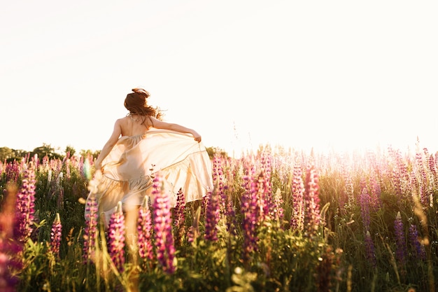 A beautiful bride in wedding dress is dancing alone in a field of wheat.