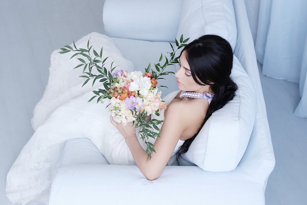 Beautiful bride in white gown holding a bouquet of flowes