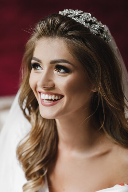 Beautiful bride in white silk robe sits on a bed in a hotel room