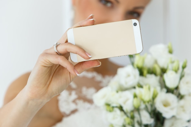 Beautiful bride with bouquet and smartphone