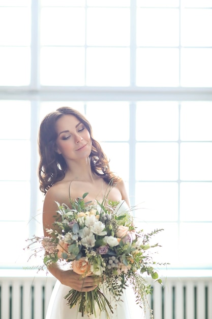 花の花束とエレガントなウェディングドレスの美しい花嫁の女性