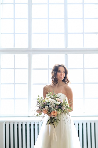 Красивая невеста женщина в элегантном свадебном платье с букетом цветов