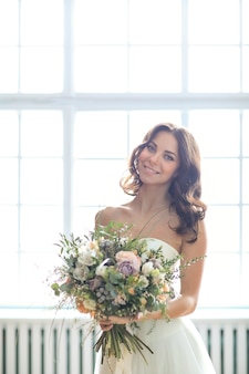 花​の​花束​と​エレガントな​ウェディング​ドレス​の​美しい​花嫁​の​女性