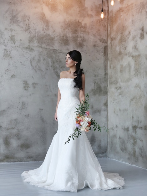Beautiful bride woman in wedding dress holding a bouquet of flowers