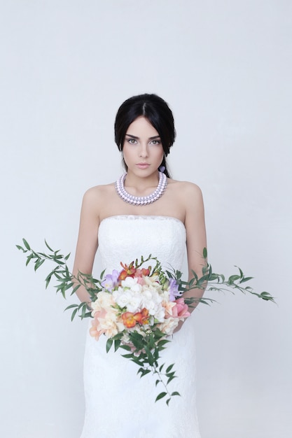 Красивая невеста женщина в свадебном платье держит букет цветов