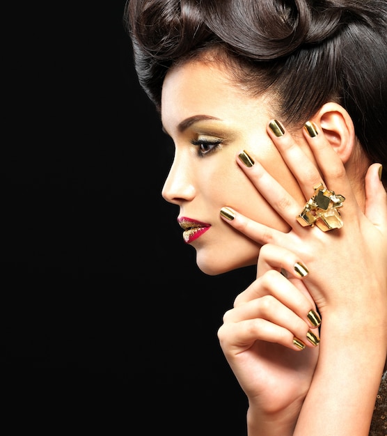 Free photo beautiful brunet woman with golden nails and style makeup of eyes -  on black wall