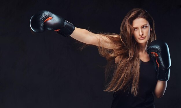 Beautiful brunette female boxer during boxing exercises, focused on process with serious concentrated facial.