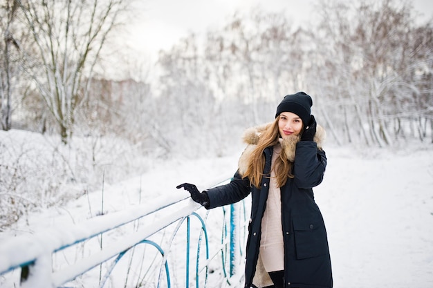 Beautiful brunette girl in winter warm clothing Model on winter jacket and black hat