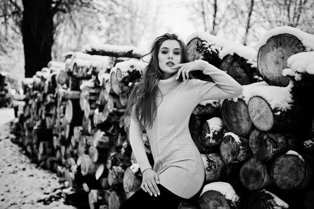 Beautiful brunette girl in winter warm clothing Model on winter sweater near stump