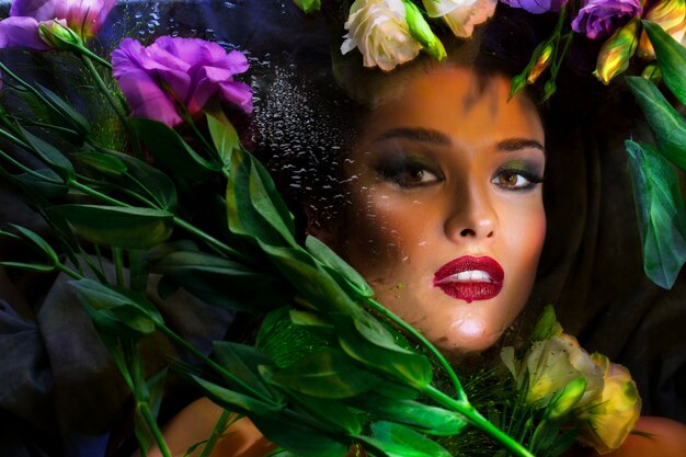 Beautiful brunette girl with bright make up lying among eustomas.