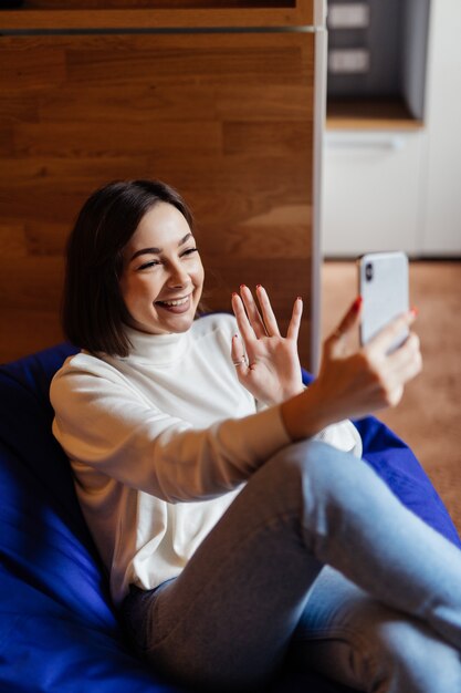 흰색 t- 짧은 selfie에 아름 다운 갈색 머리 아가씨는 그녀의 전화에 화상 통화가