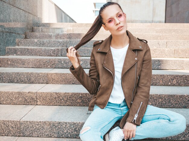 Beautiful brunette model dressed in summer hipster jacket and jeans clothes    Playing with hair