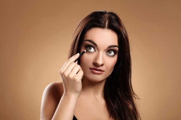 Beautiful brunette with makeup pencil